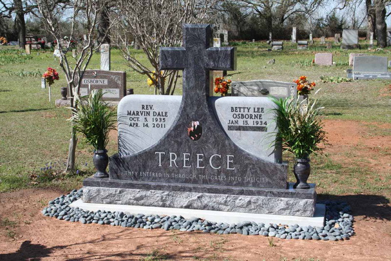 Grey granite companion monument with a carved cross, standing in a Texas cemetery