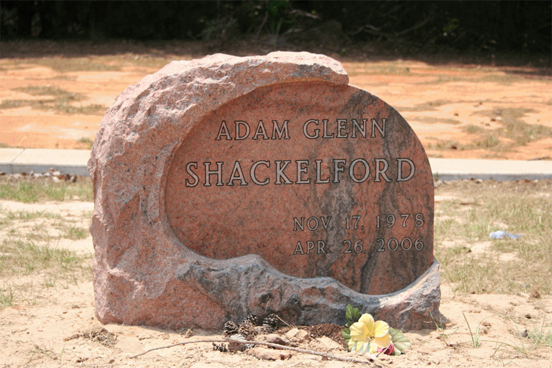 Red granite boulder monument with a rough natural edge and a polished lettering panel