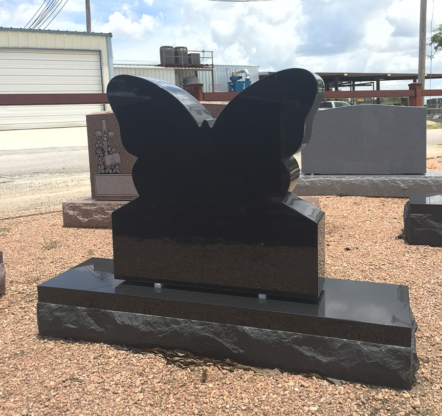 Black granite monument cut to the shape of a butterfly on a rough hewn base